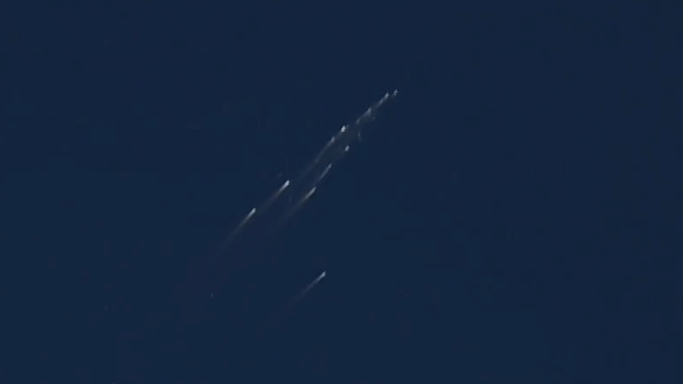 航天图片资料 · view of a satellite breaking apart, showing a dozen or so bright streaks in a blue sky