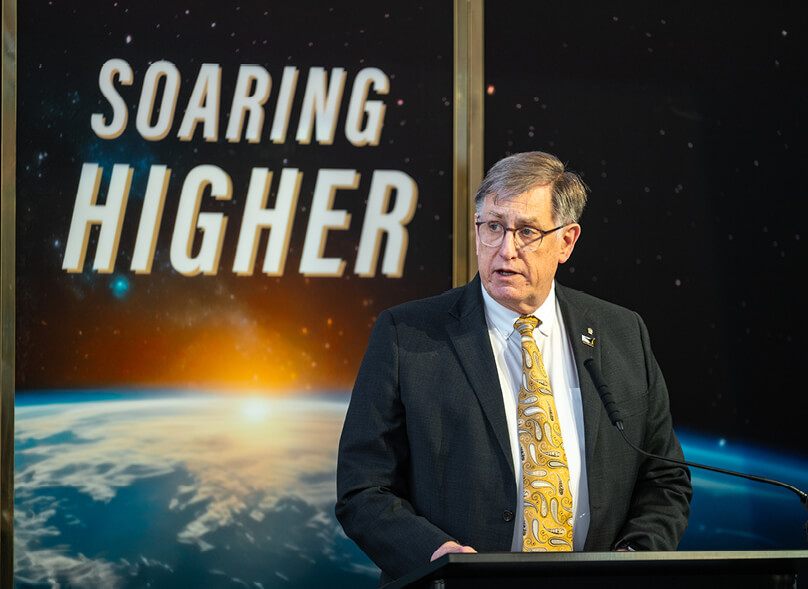 航天图片资料 · Dan Dumbacher speaks at a podium in front of a backdrop that says “Soaring Higher”