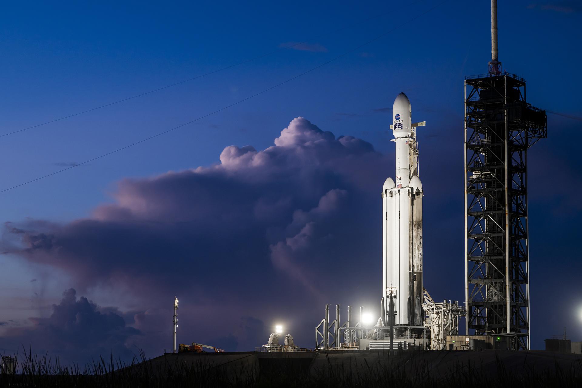 航天图片资料 · A white SpaceX Falcon Heavy rocket stands vertical on the black launch pad with a predawn sky in the background.