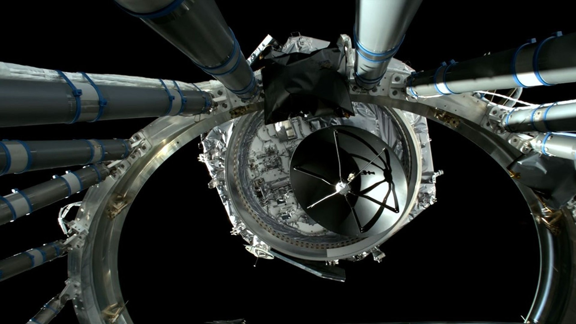 航天图片资料 · a hexagonal spacecraft floats away from a large metal ring on a black background