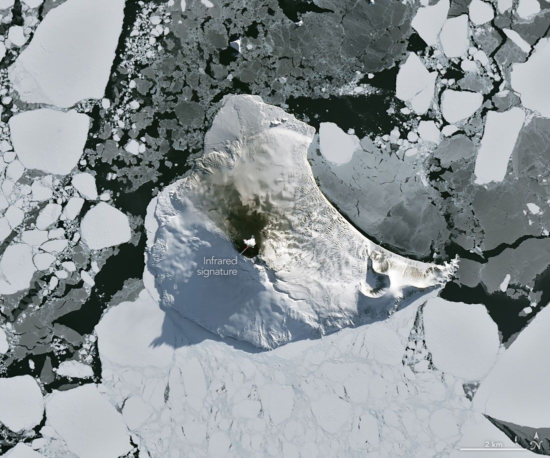 航天图片资料 · A small ice- and snow-covered island with an active volcanic crater at its center is surrounded by drifting pieces of sea ice. A thermal signal and small plume appear in the crater, and ash darkens the snow on the volcano’s northern slopes.