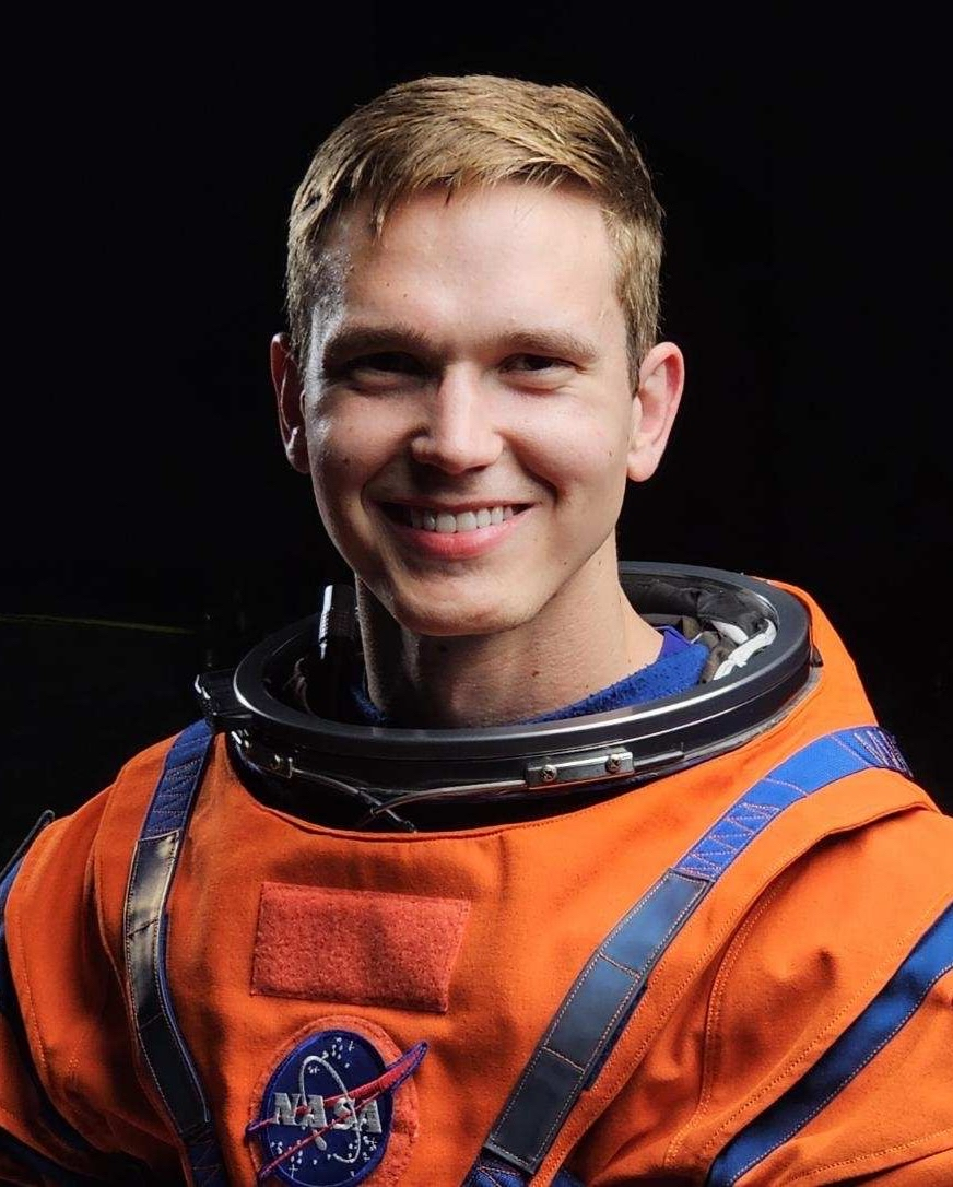 航天图片资料 · A man poses and smiles wearing an orange spacesuit.