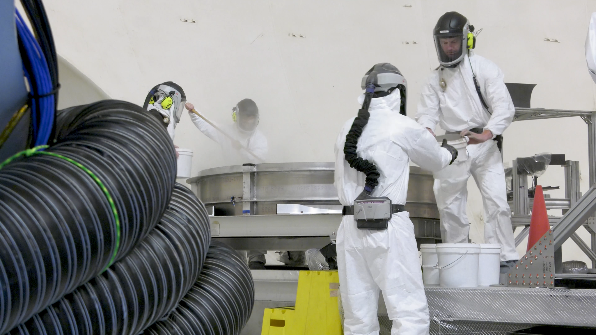航天图片资料 · A crew loads simulated lunar dirt into the test bin in the 60' vacuum sphere.