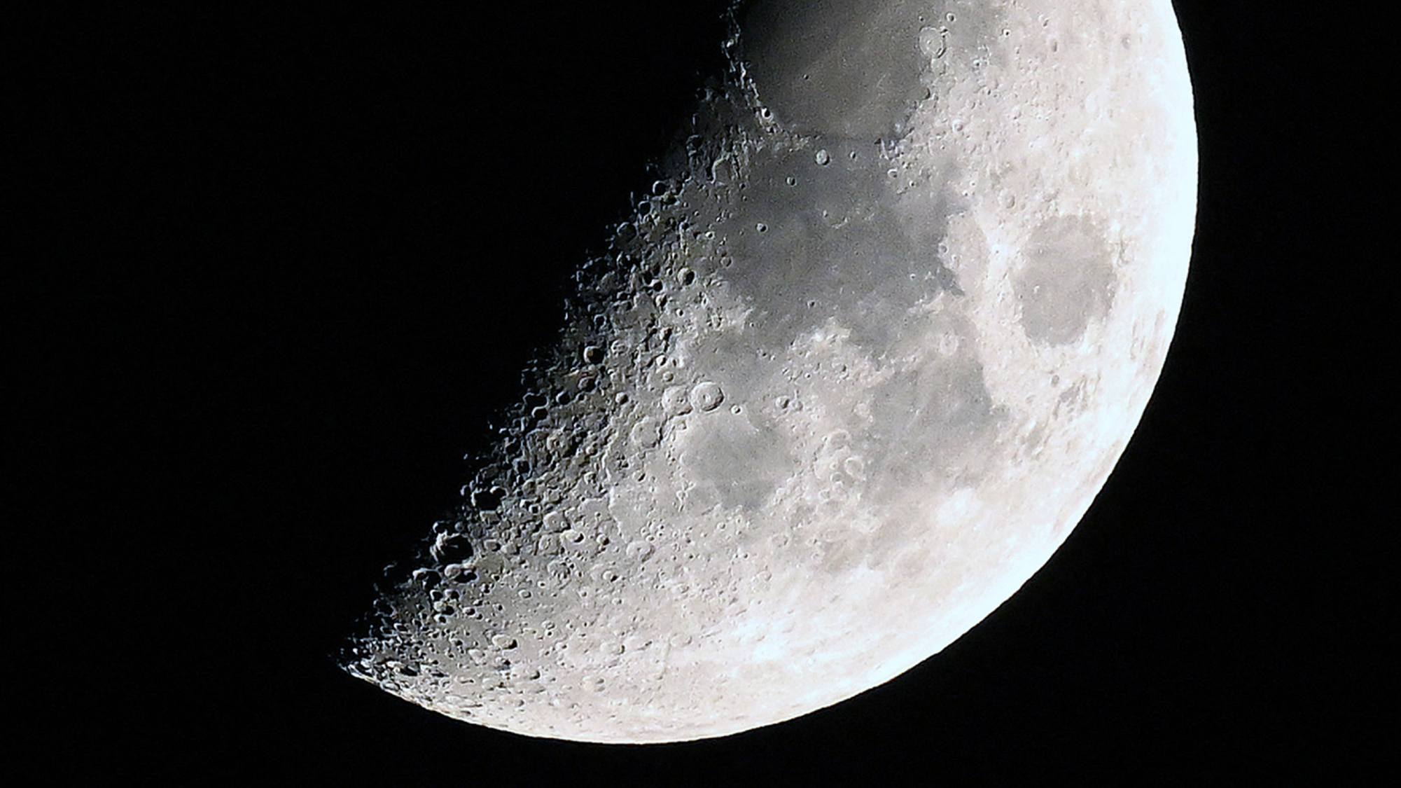 航天图片资料 · A photo of the moon with its right side lit around the first quarter phase in a black sky.