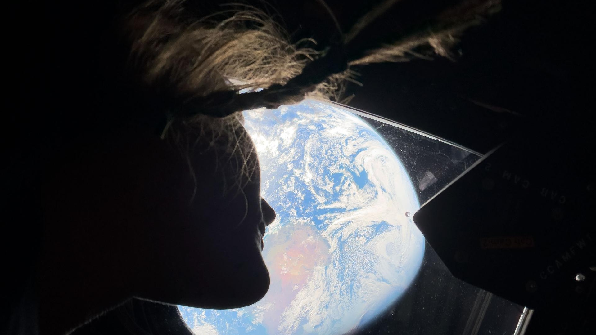 航天图片资料 · The silhouette of a woman looking out the window at Earth.