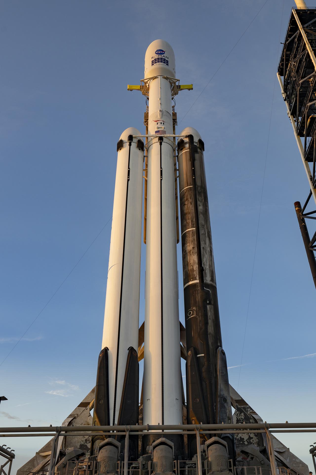 航天图片资料 · A white SpaceX Falcon Heavy rocket stands vertical on the black launch pad with a predawn sky in the background.