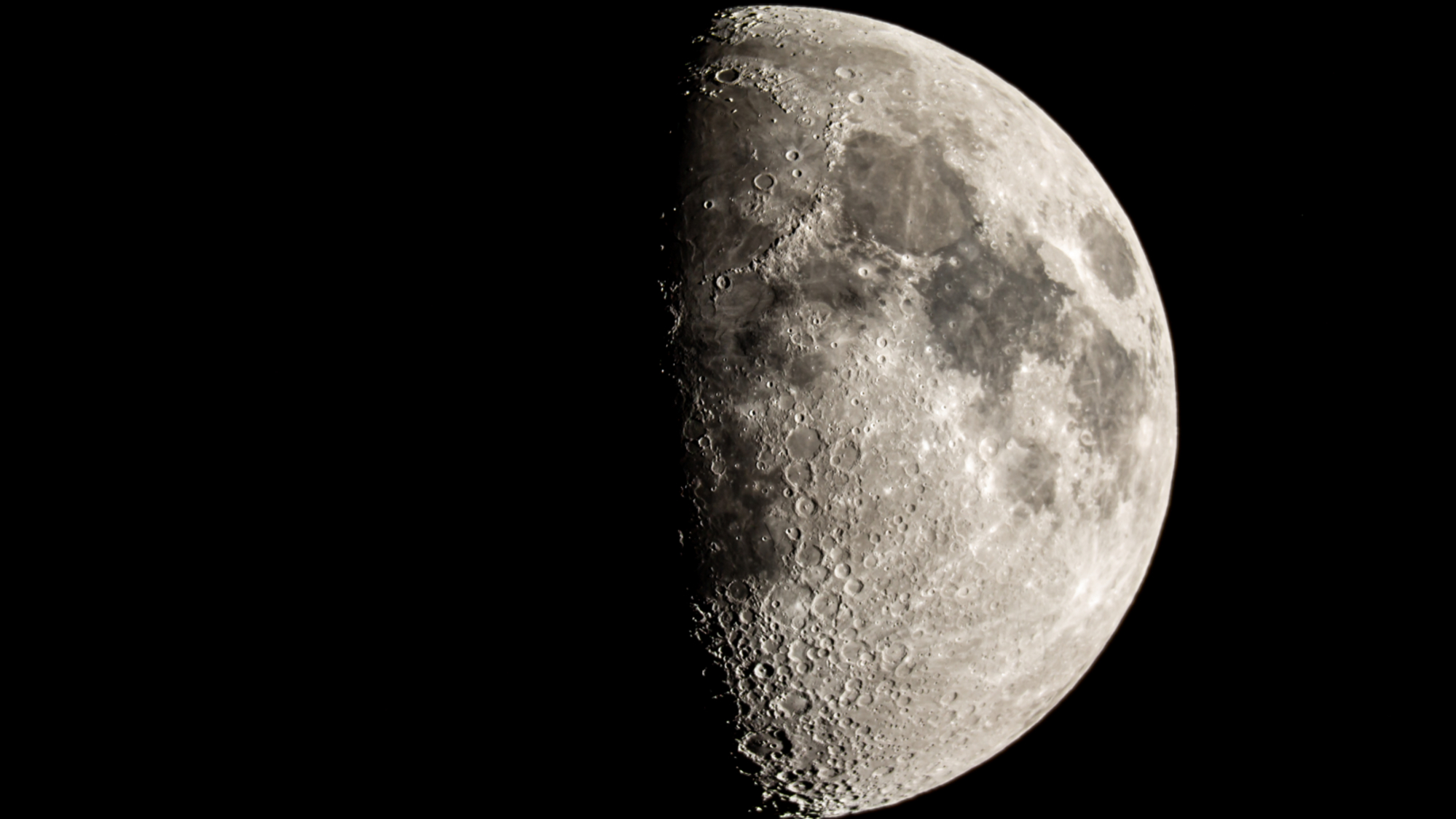 航天图片资料 · The moon is photographed with its right side lit by sunlight in a black night sky.