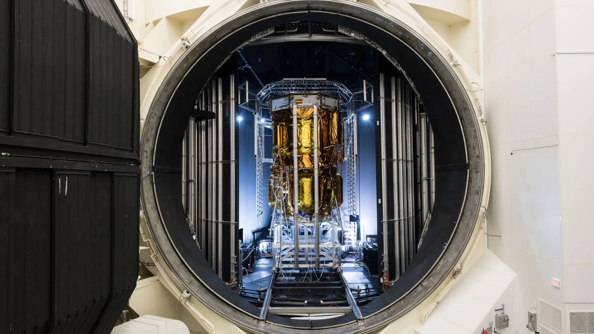 航天图片资料 · a gold-foiled spacecraft stands in a chamber with an open hatch