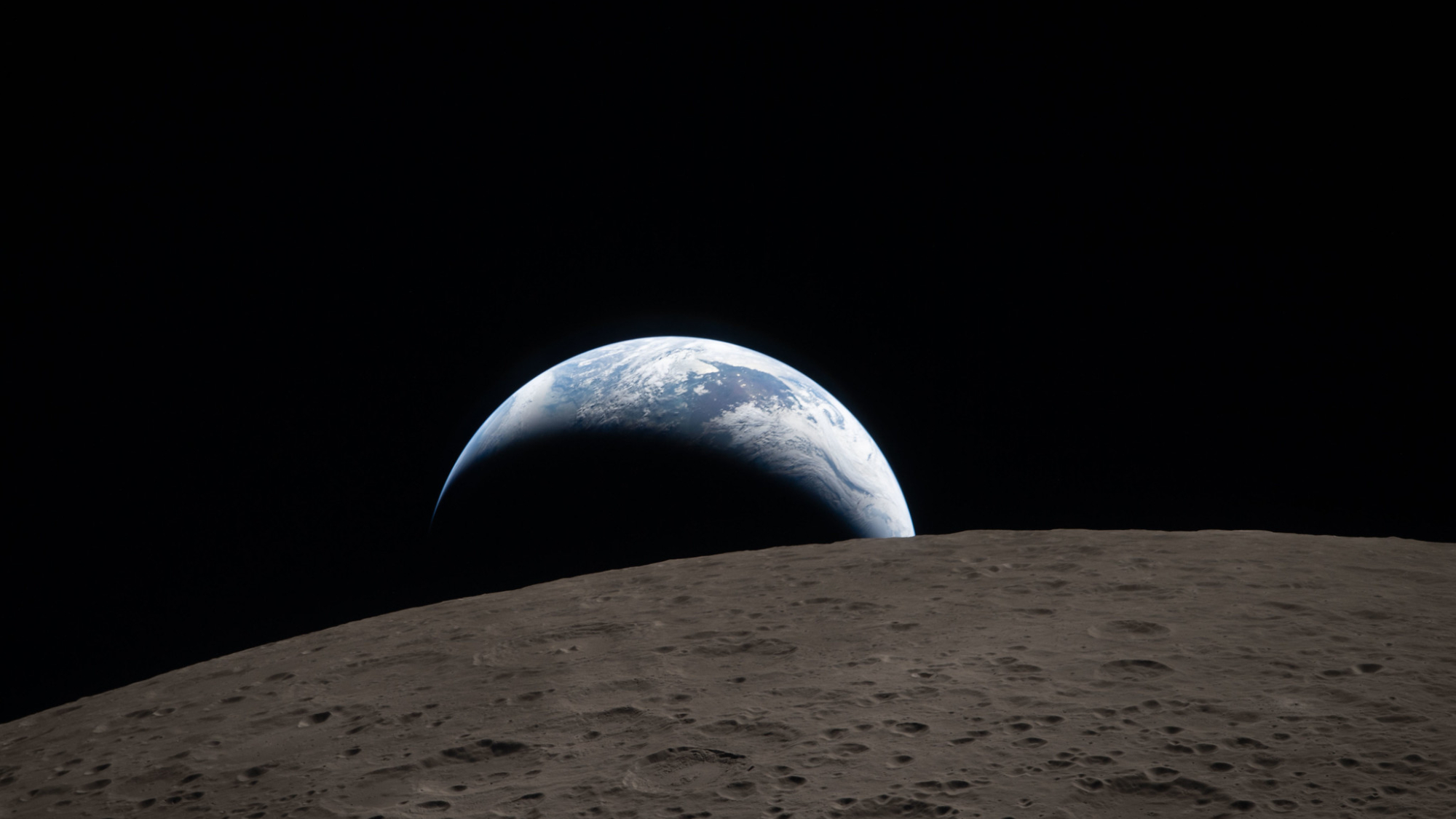 航天图片资料 · spacecraft photo showing a crescent earth setting above the curved, gray, crater-pocked surface of the moon