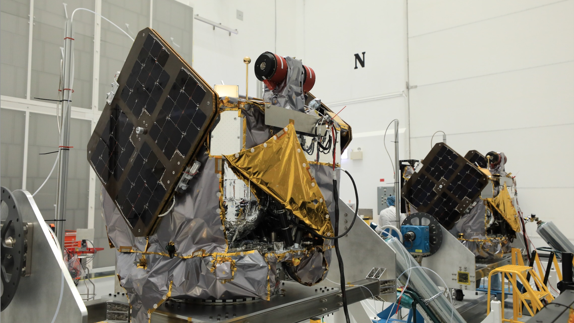 航天图片资料 · two silver and gold spacecraft sit in a white-walled clean room