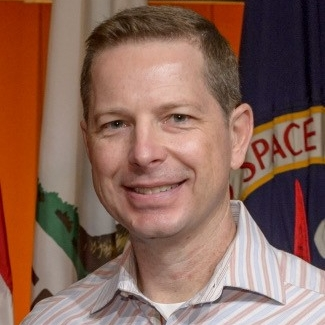 航天图片资料 · A portrait shot of Steve Ormsby in front of a NASA flag.