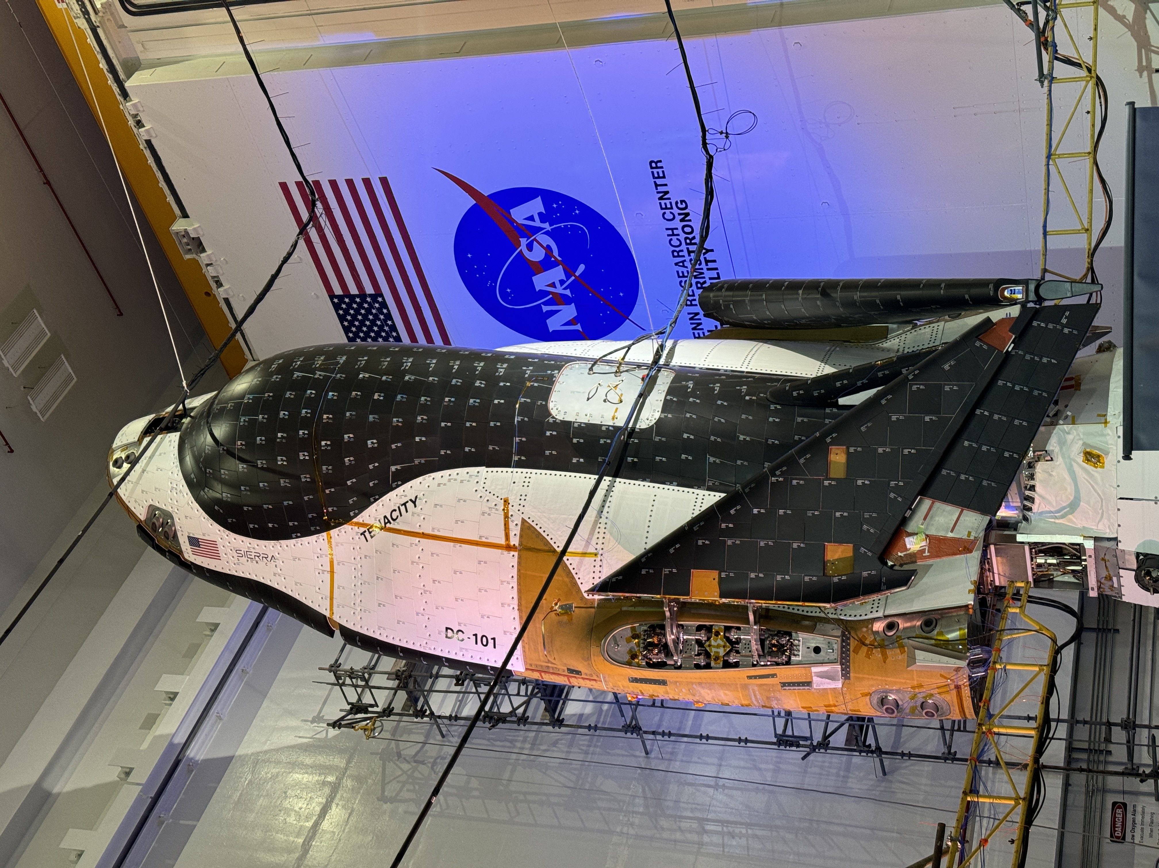 航天图片资料 · a black and white space plane stands on end in folded up in a hanger.