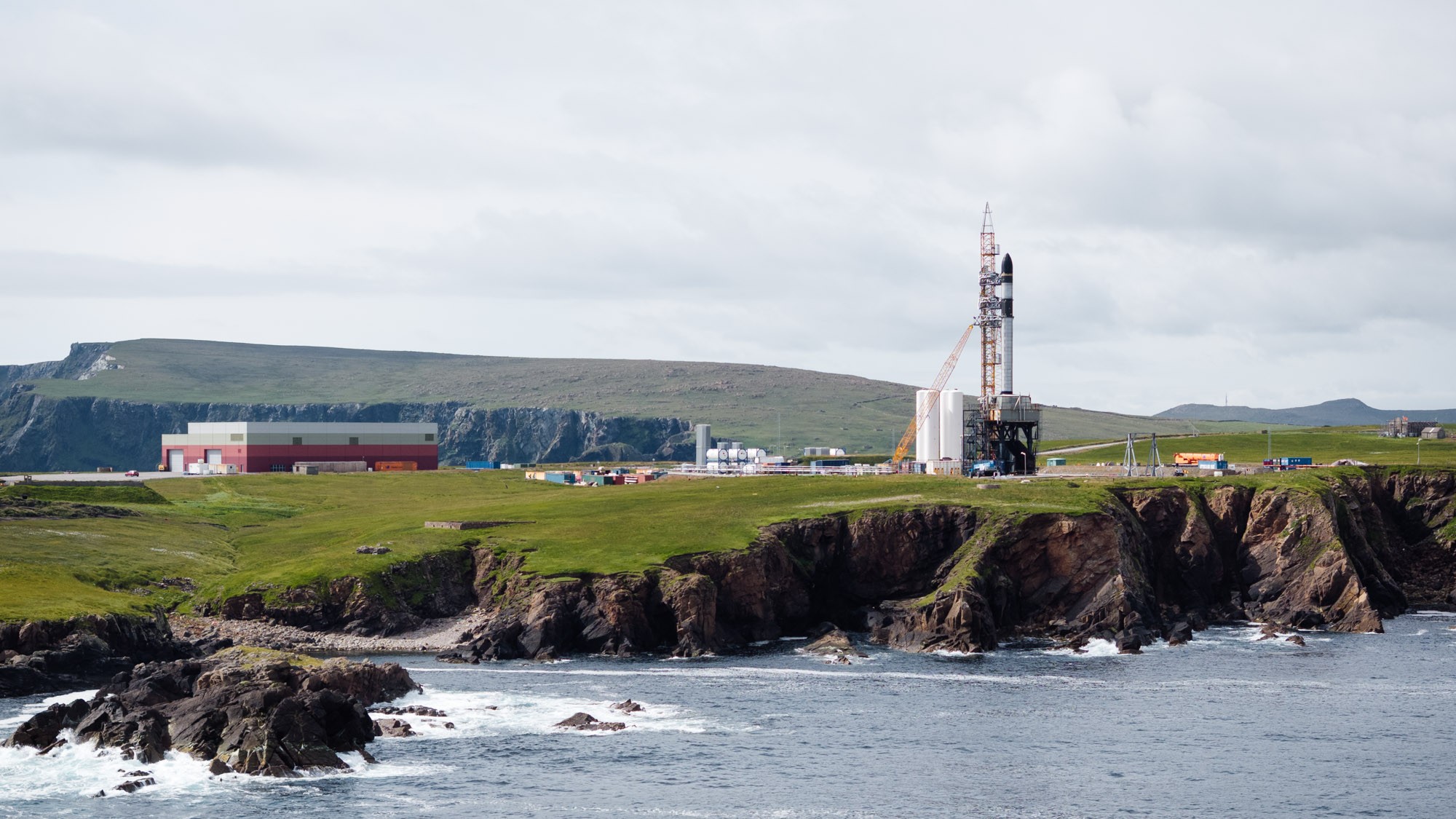 航天图片资料 · a rocket stands upright on a launch pad on a rocky outcrop beside the sea