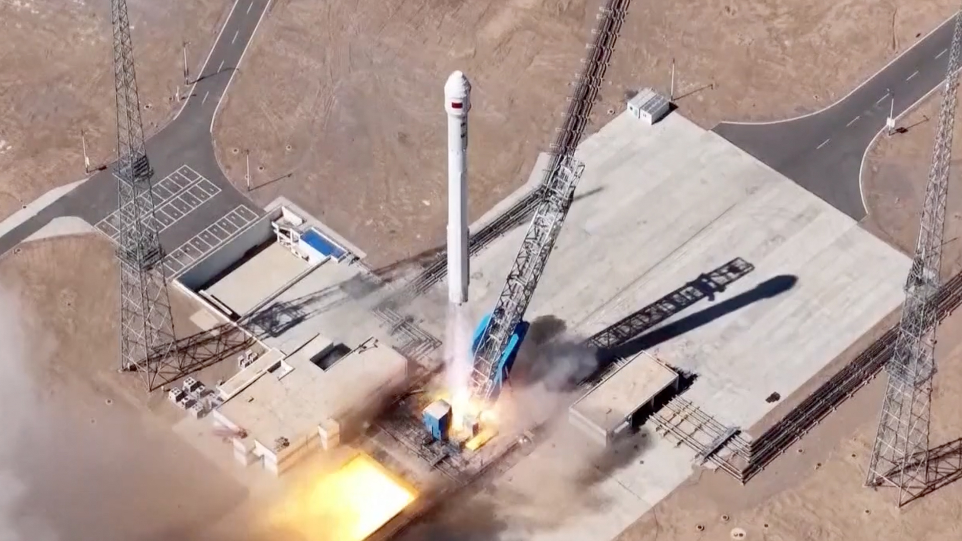 航天图片资料 · overhead drone photo of a white rocket launching from a desert pad