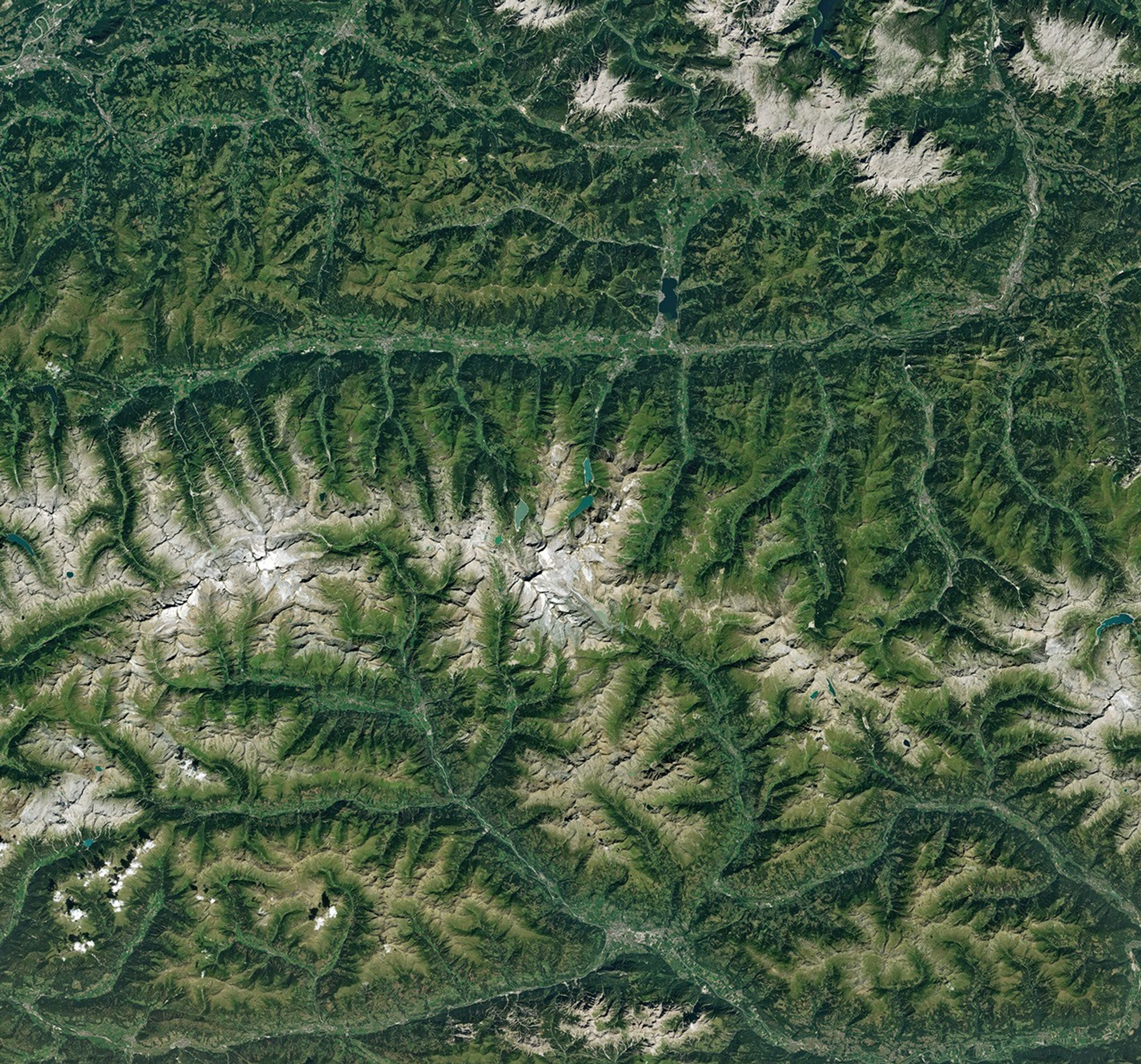 航天图片资料 · Ice in a broad Alpine basin connects with a short, narrow stretch of glacial ice in the valley below through one small icefall. Lakes fill much of the valley beyond the glacier’s terminus.