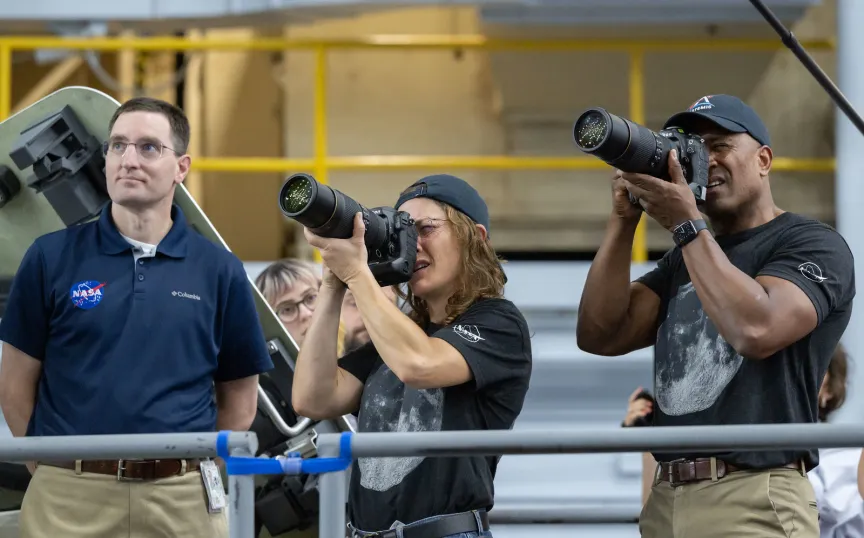 航天图片资料 · A man and a woman holding DSLR cameras with long lenses train how to use them.