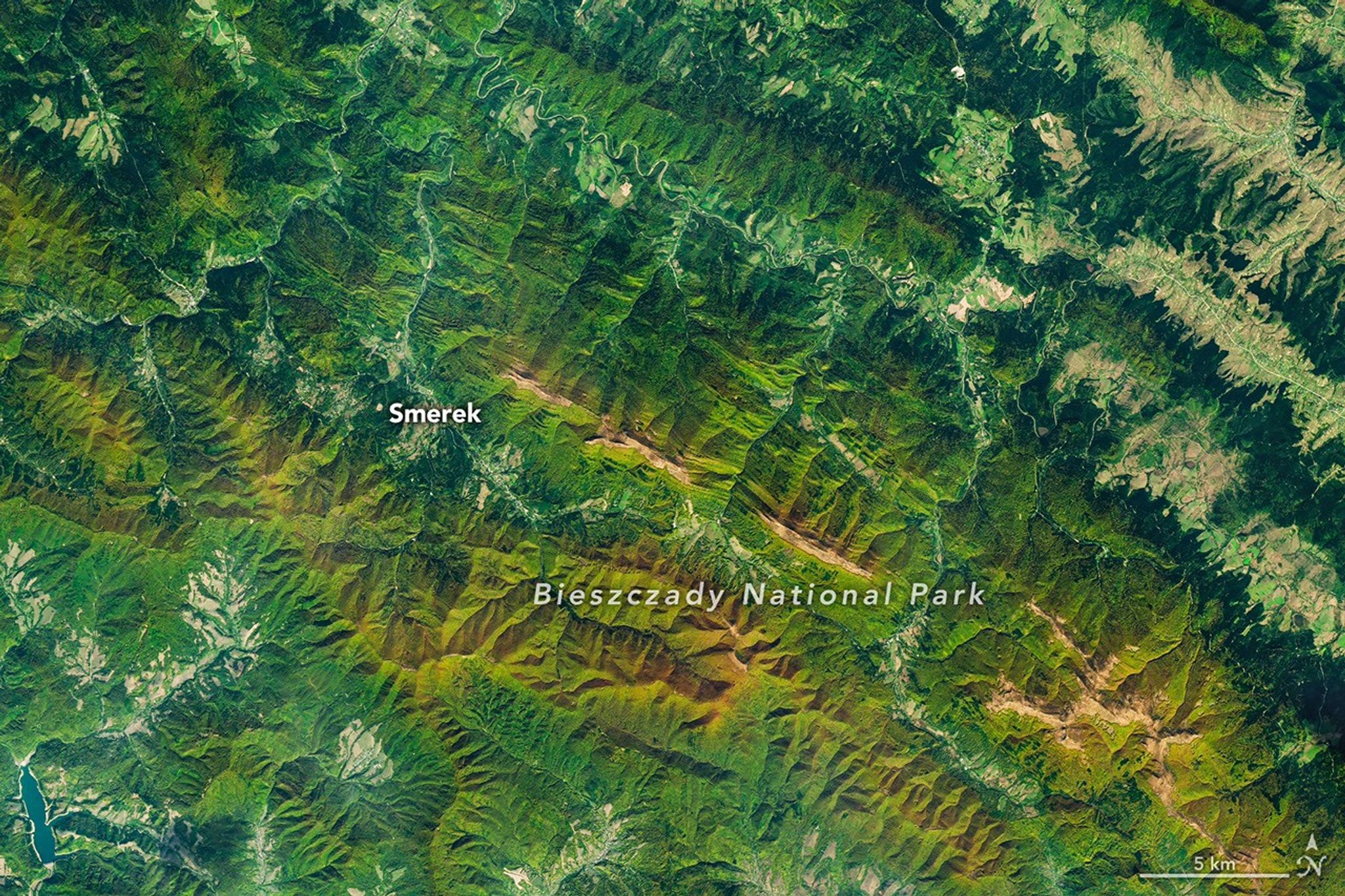 航天图片资料 · A satellite image of mountains in southeastern Poland in autumn. Green and orange forest covers parallel ridges running diagonally across the scene, and tan grasslands stretch along the highest crests.