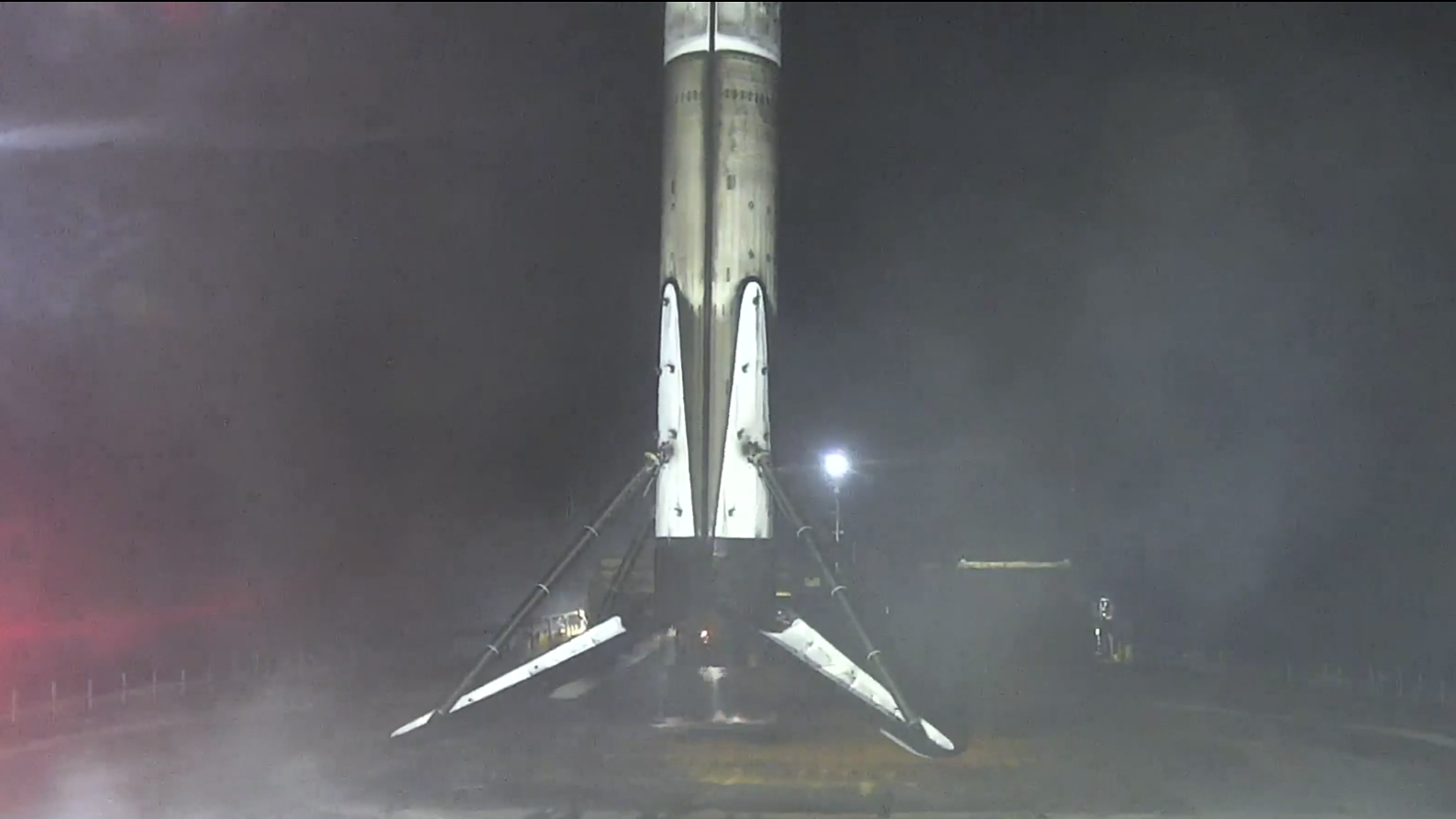 航天图片资料 · A charred white rocket stands with legs extended on a dark barge at sea.