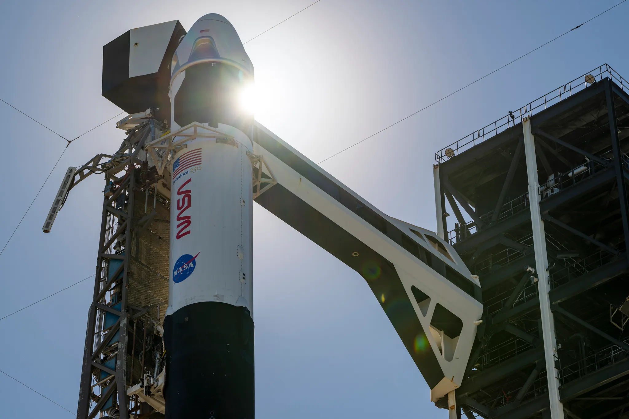 航天图片资料 · A rocket stands vertical at the launch pad, connected to the launch tower by a crew access arm.