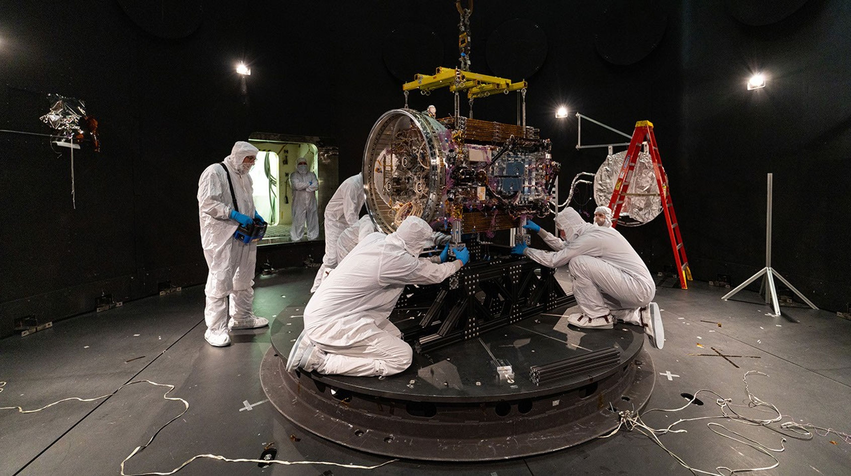航天图片资料 · People in clean suits work on a spacecraft in a large chamber.
