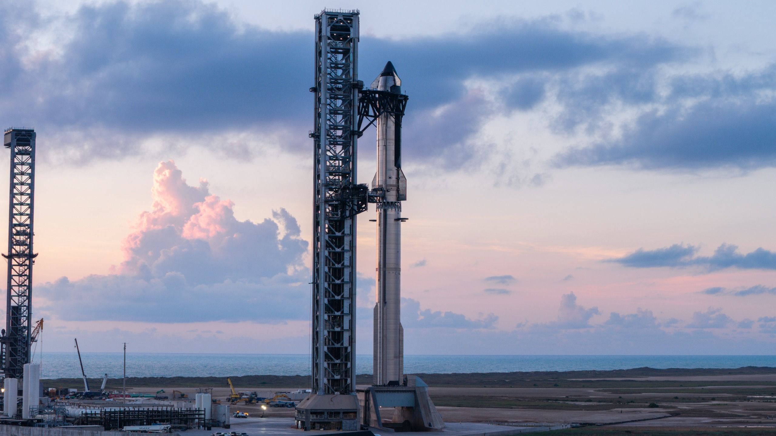 航天图片资料 · A towering SpaceX Starship rocket stands at Starbase's Pad 2, bathed in chrome against a dusk/dawn blue sky.