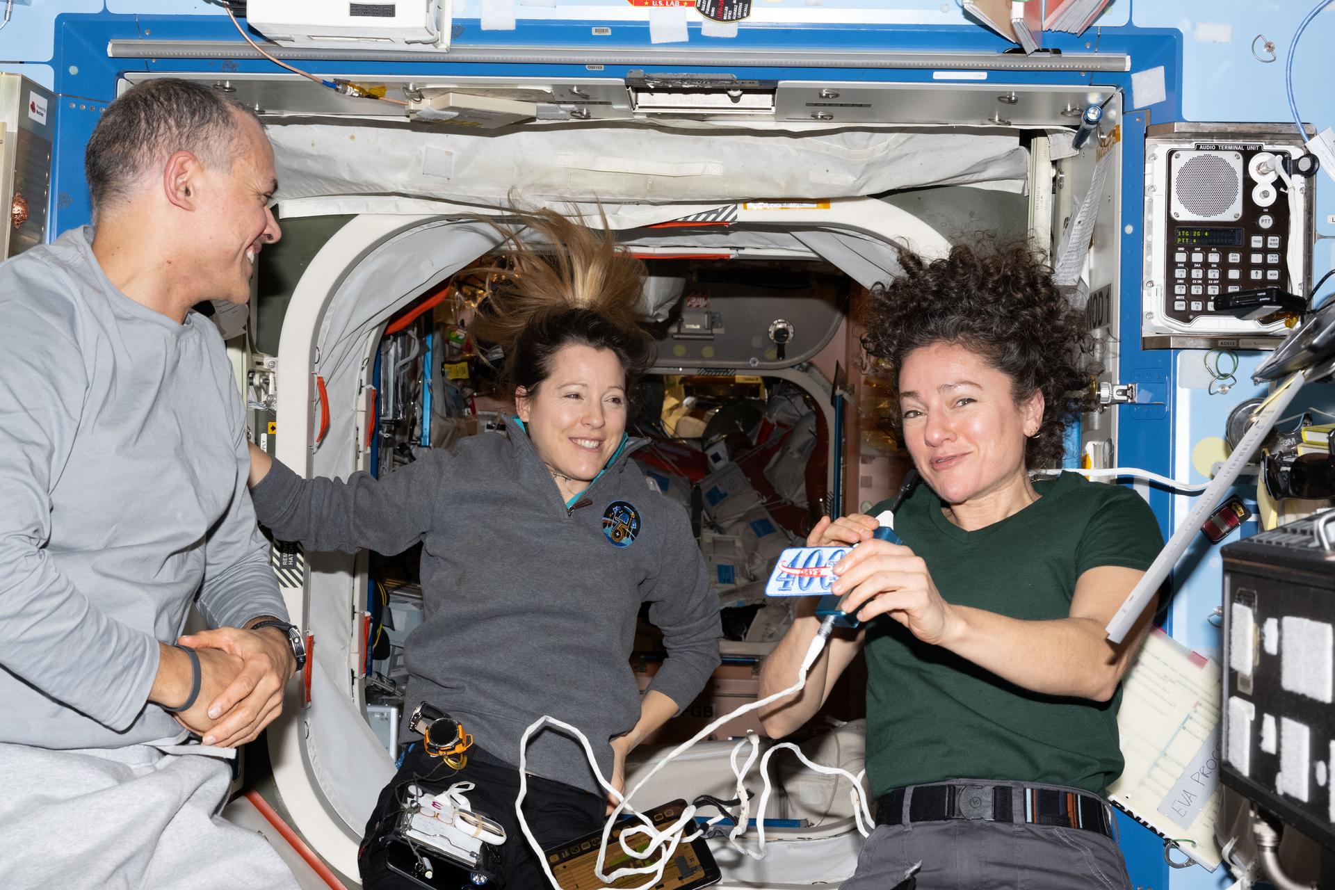 航天图片资料 · Expedition 75 flight engineers Anil Menon of NASA and Sophie Adenot of ESA (European Space Agency) and International Space Station commander Jessica Meir of NASA gather together inside the International Space Station's Destiny laboratory module. Meir is holding a patch given to her commemorating 400 cumulative days in space (and counting) across two missions to the orbital outpost.
