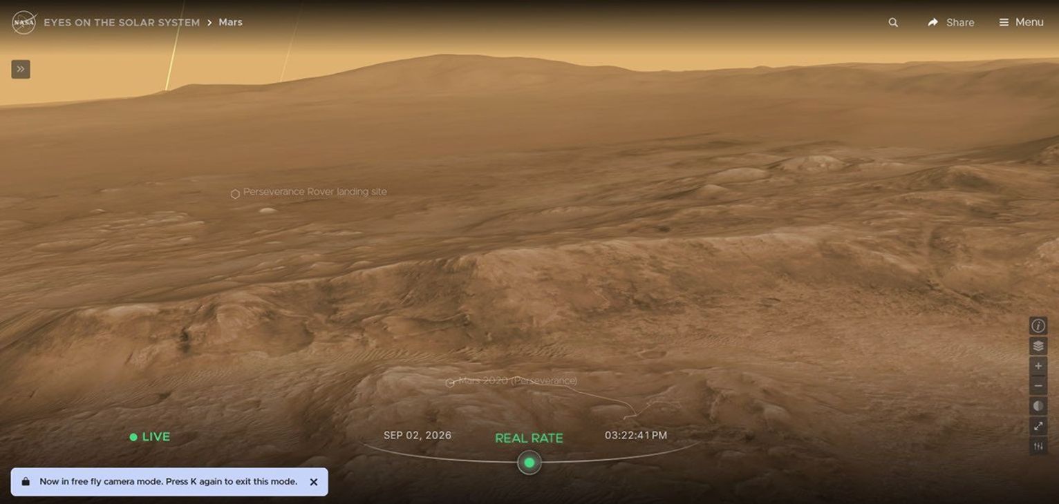 航天图片资料 · An image above the terrain of Mars far above the Perseverance rover in 3D, with text that explains the the user has entered free-fly mode by pressing "k" on their keyboard.
