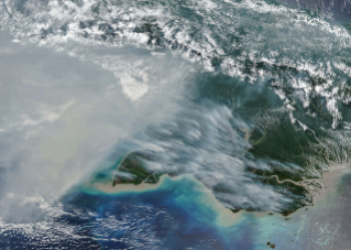 航天图片资料 · Smoke covers much of the southern third of New Guinea, while clouds and east-west-running mountain ranges are visible in the northern part of the island.