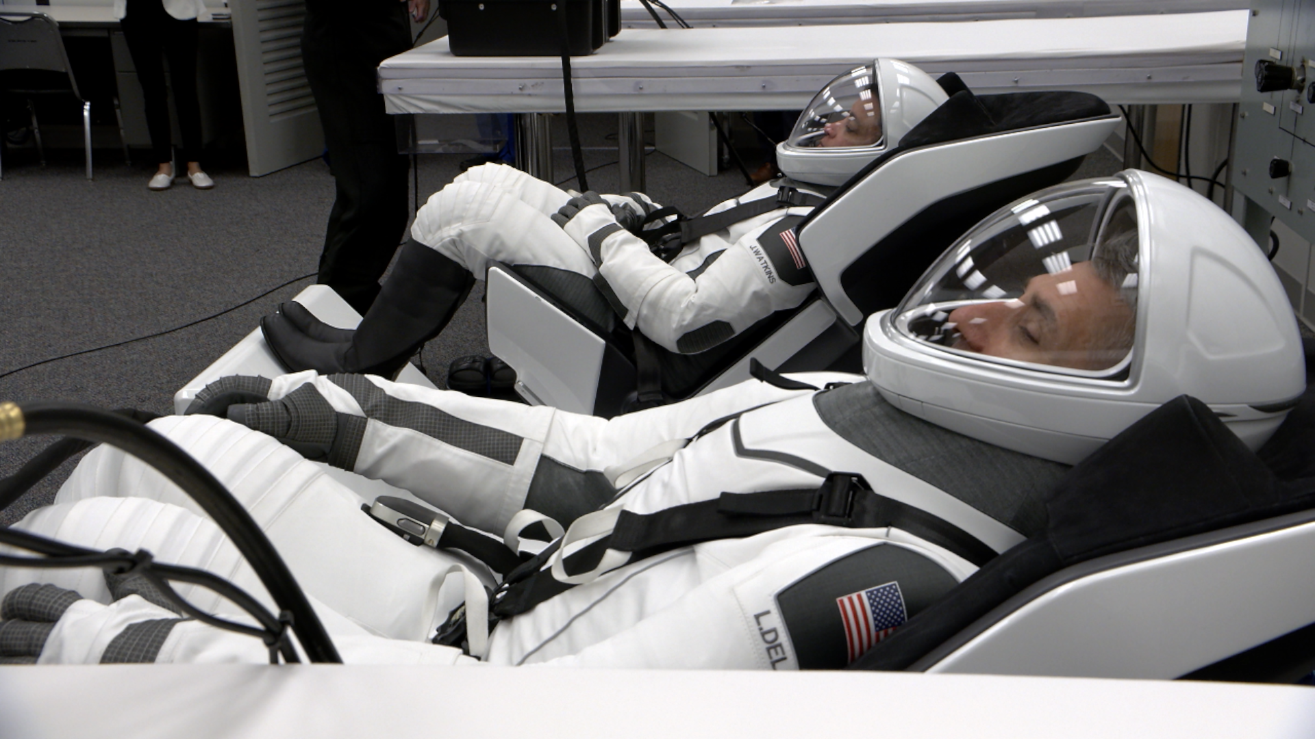 航天图片资料 · Astronauts in white spacesuits lying down during suit checks.