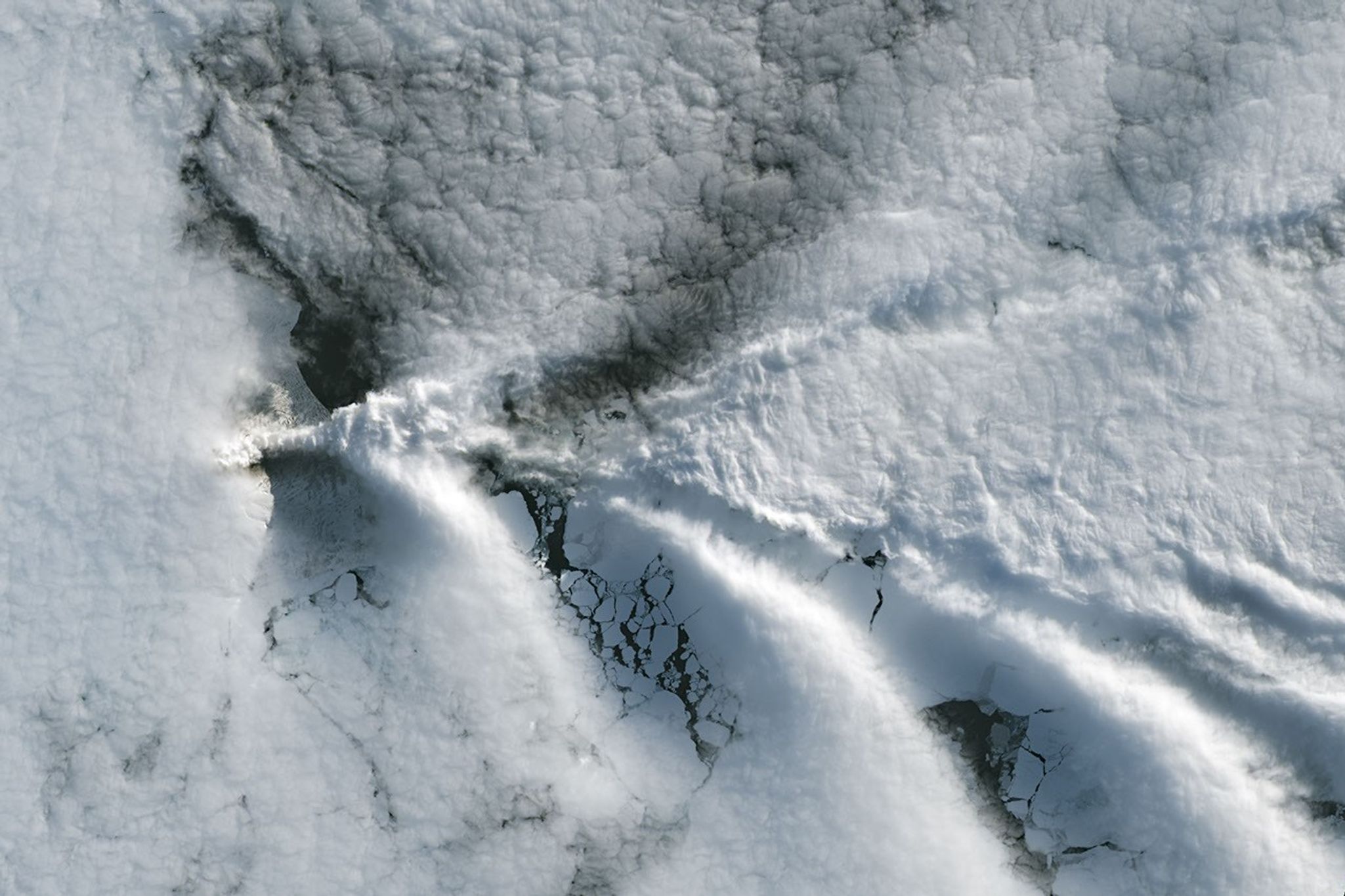 航天图片资料 · A series of V-shaped wave clouds appears over an ocean filled with pieces of sea ice.
