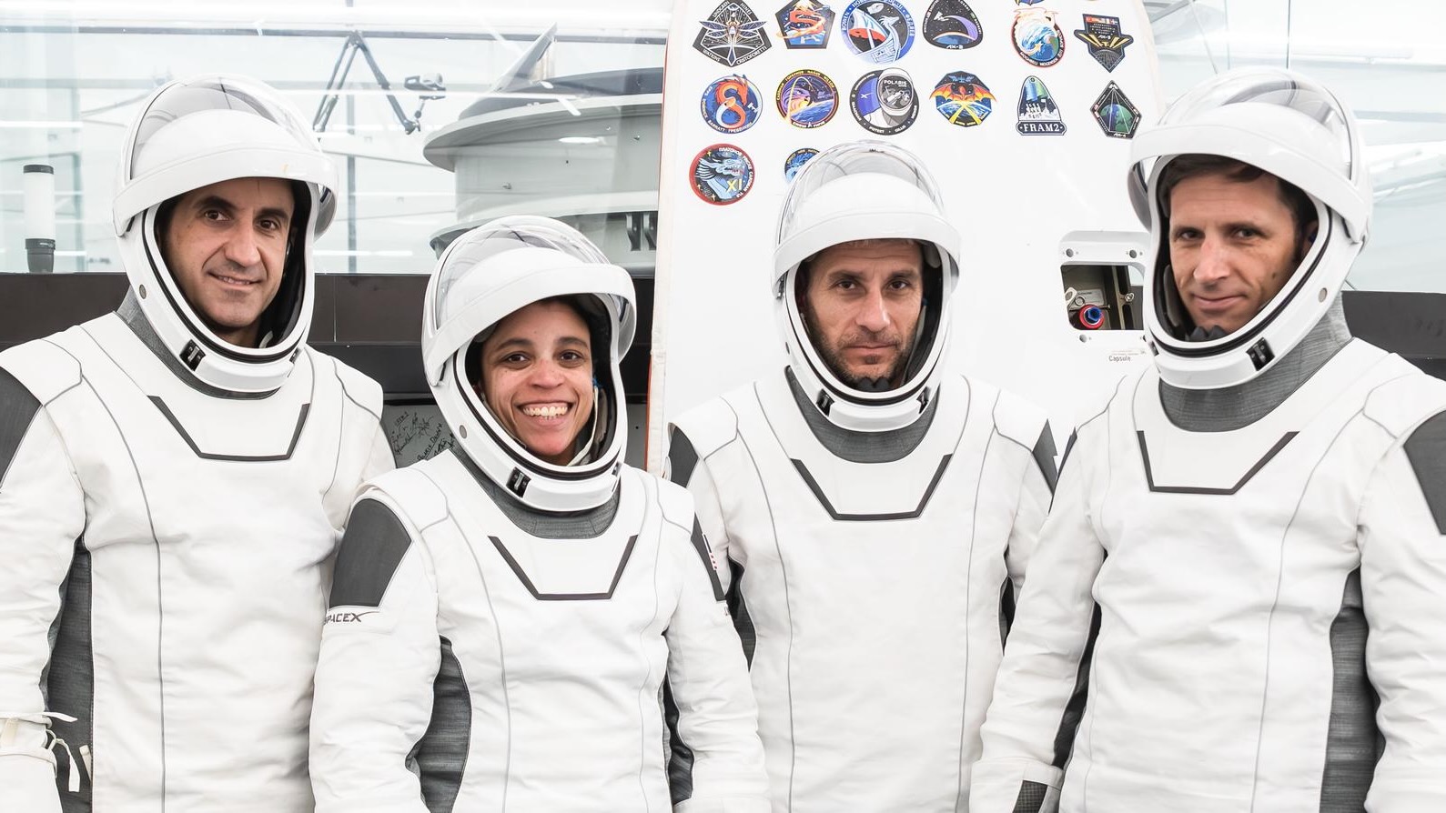 航天图片资料 · three male and one female astronauts in white flight suits stand in a big, white-walled room