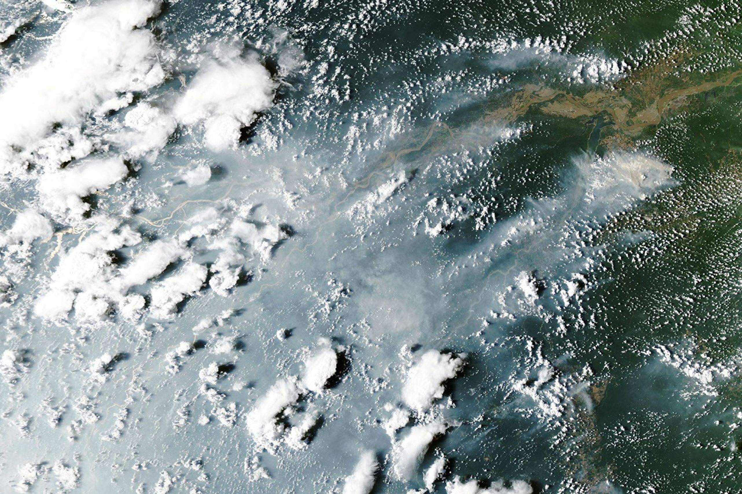 航天图片资料 · Thick gray smoke partially obscures the Amazon River and surrounding rainforest near the cities of Manaus and Santarém. Puffy white clouds rise above the smoke on the left side of the image.