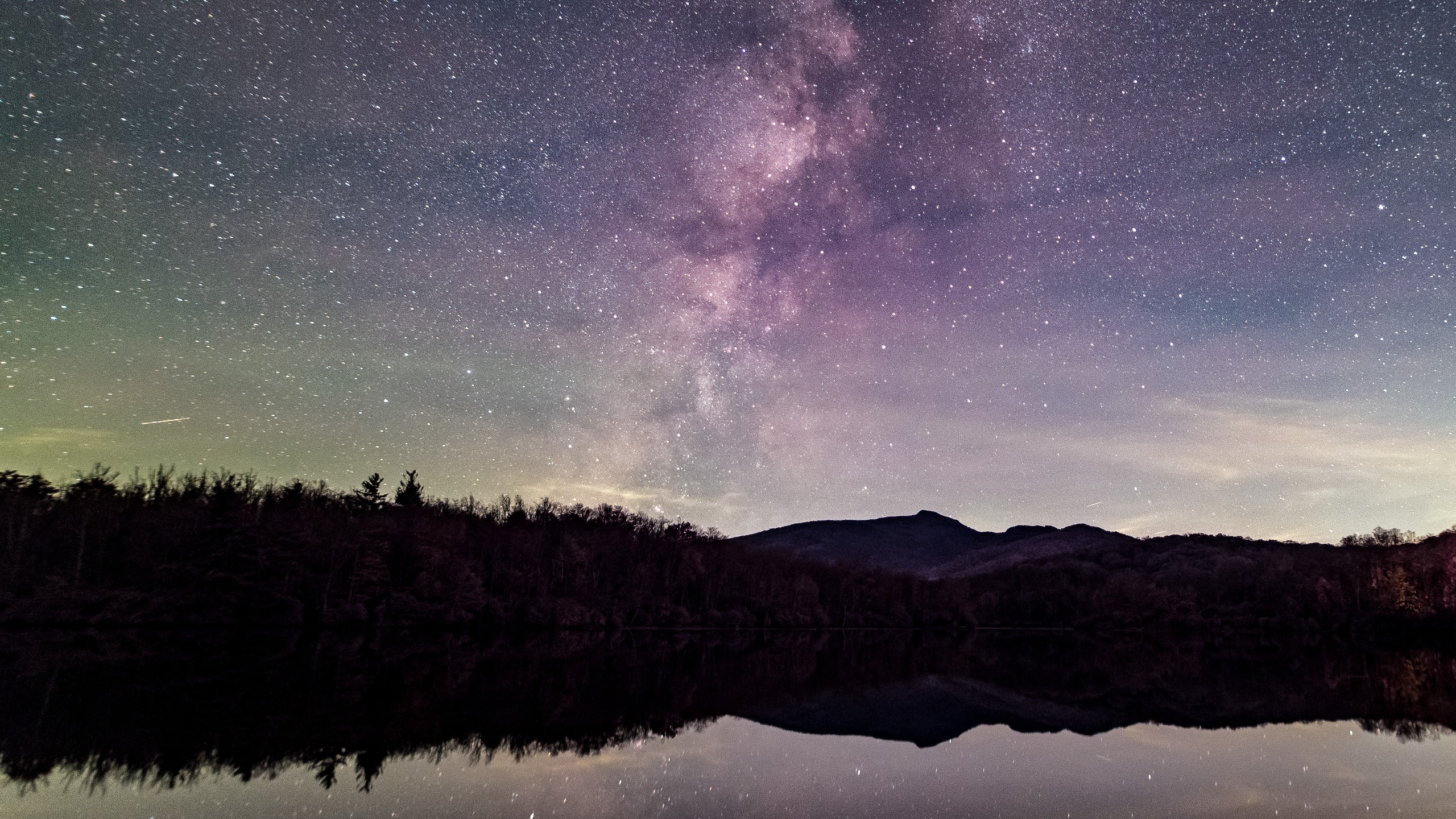 航天图片资料 · starry night above a lake. the milky way stretches up from behind silhouetted trees to fill the center portion of the sky in the image.