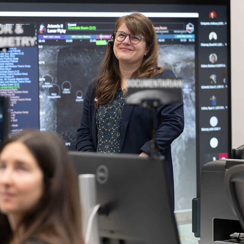 航天图片资料 · Marie Henderson, standing, and fellow members of the Artemis lunar science team listen as the Artemis II crew shares observations during the lunar flyby