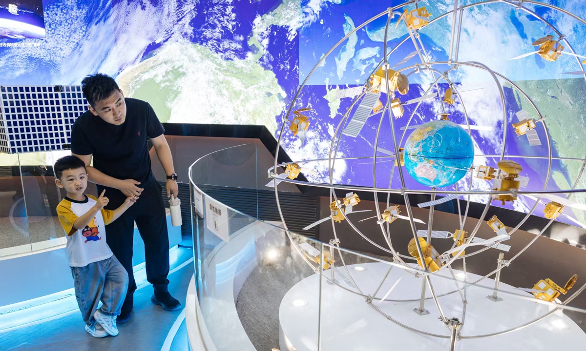 航天图片资料 · A man and a child observe a model of satellite constellations on display, featuring orbiting spacecraft encircling a miniature Earth, at the China Space Museum in Beijing, China, on April 24, as the day marks the 11th China Space Day, which this year coincides with the 70th anniversary of China's space program. Photo: Li Hao/GT