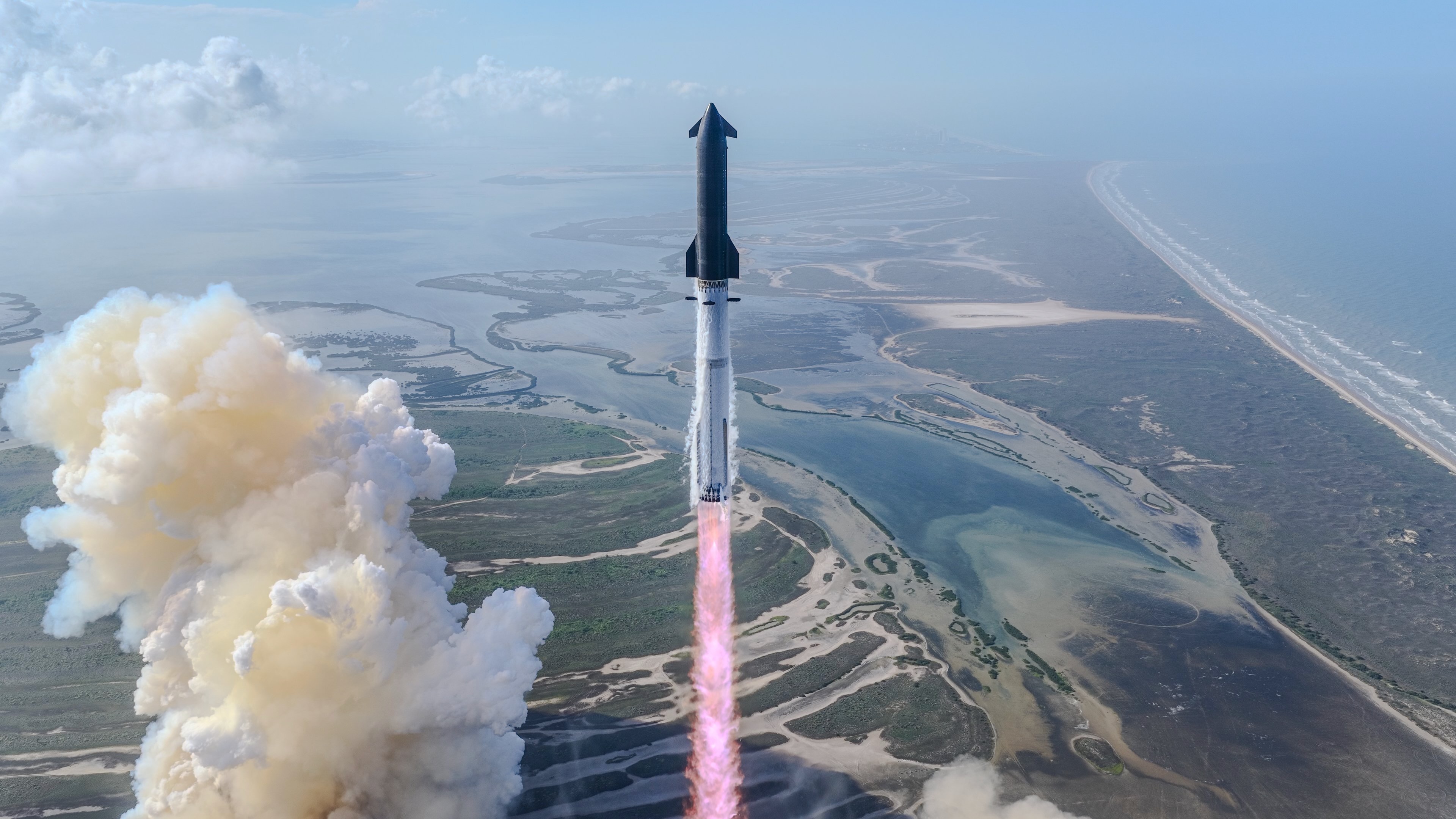 航天图片资料 · a big silver and black rocket launches from a seaside pad