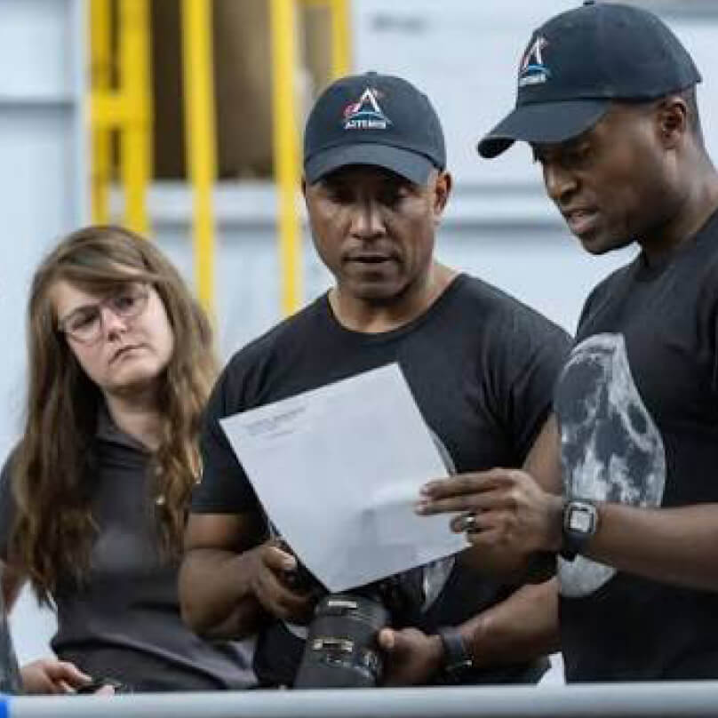 航天图片资料 · Marie Henderson looks on as a pair of colleagues review a document