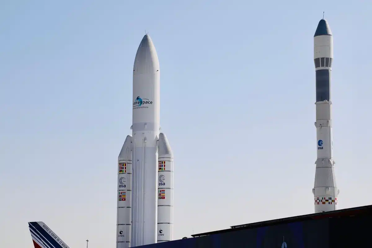 航天图片资料 · A massive booster standing vertical on a launch pad, all 33 engines glowing white-hot at the base, exhaust plumes billowing outward, the test structure surrounding the rocket backlit by the engine fire, capturing the moment of full-power ignition