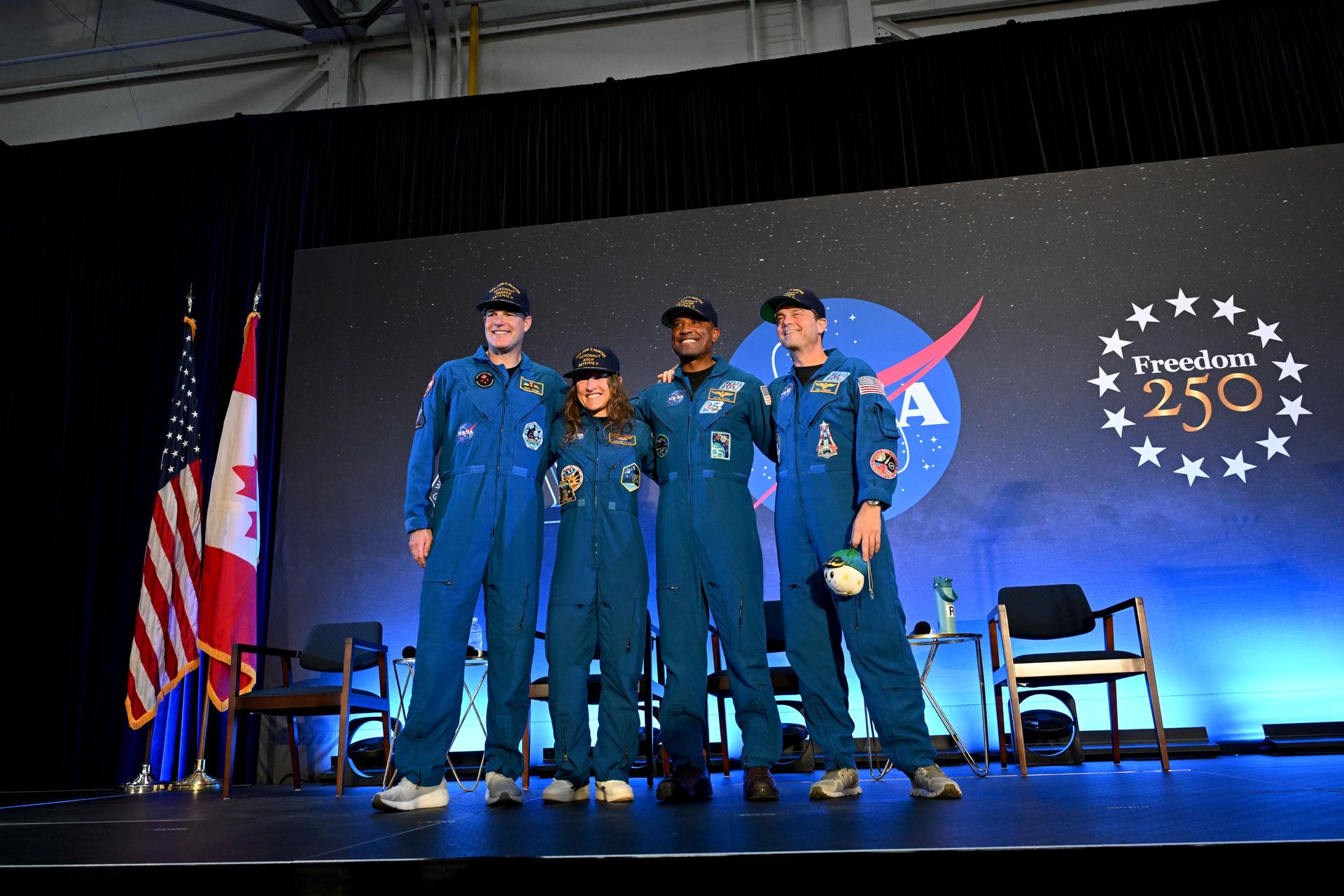 航天图片资料 · The four Artemis II crew members stand side-by-side and smiling in their blue flight suits on a stage at NASA Johnson. Bel