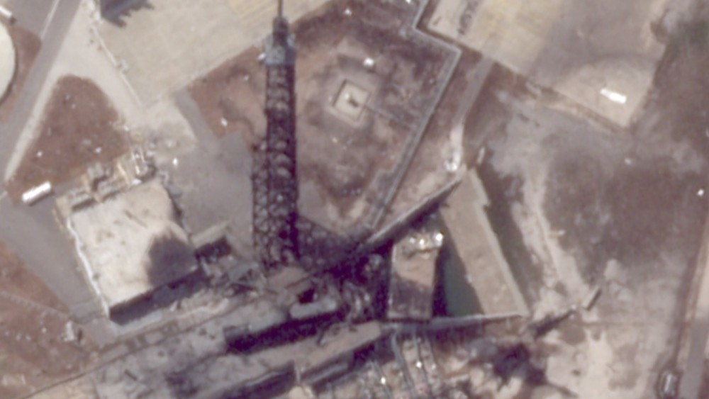 航天图片资料 · A charred black tower stands over debris after an exposion.