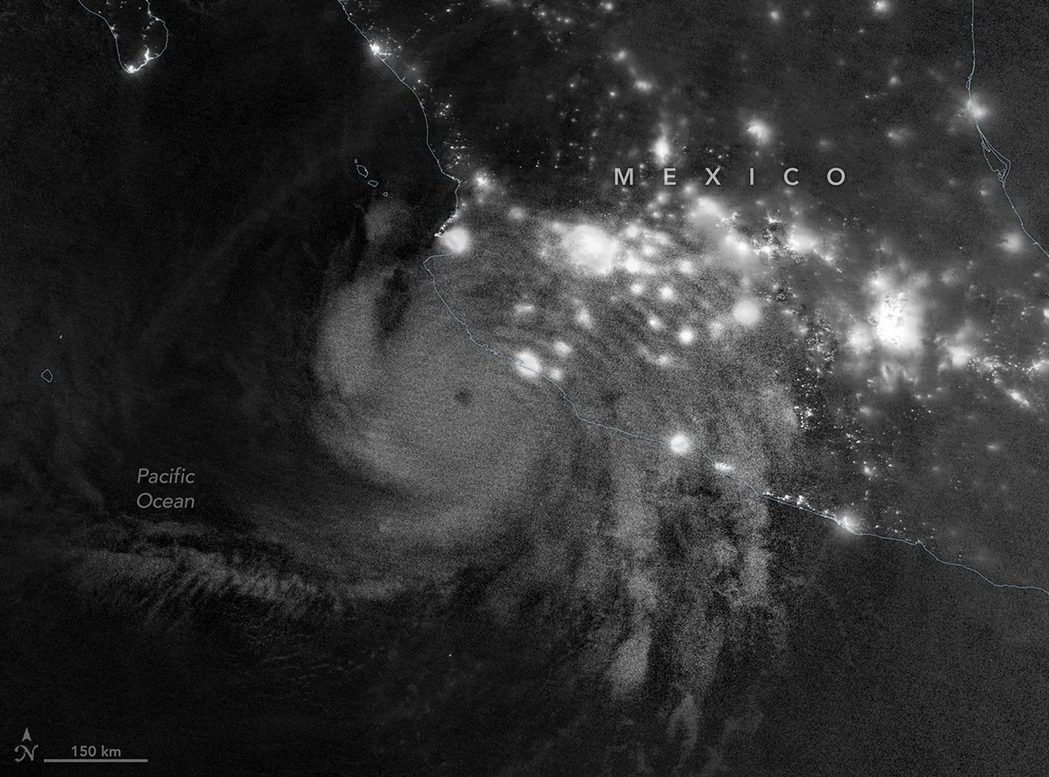 航天图片资料 · Gravity waves in the upper atmosphere appear as a semicircle of ripples in a nighttime, grayscale satellite image. Hurricane clouds and city lights in Mexico are also visible.