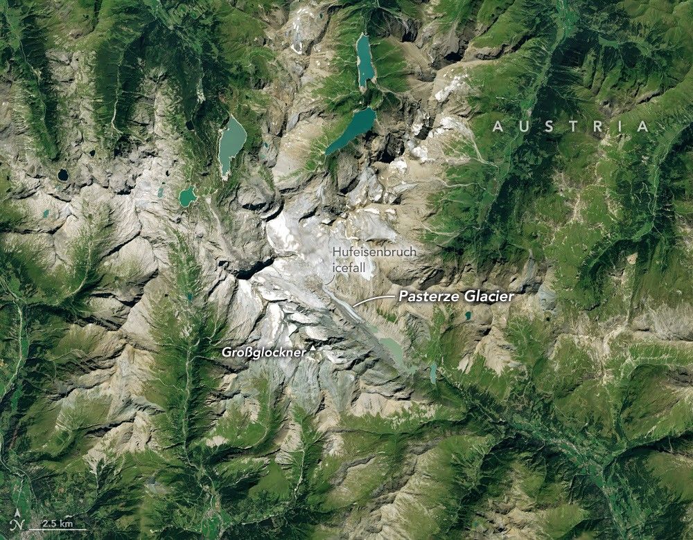 航天图片资料 · Ice in a broad Alpine basin connects with a short, narrow stretch of glacial ice in the valley below through one small icefall. Lakes fill much of the valley beyond the glacier’s terminus.
