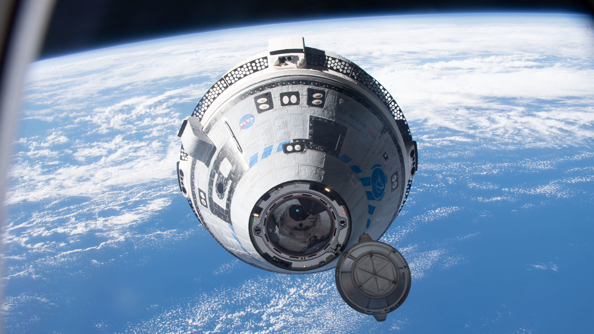航天图片资料 · A white and blue Boeing Starliner capsule floats above a blue Earth with the black of space in the background.