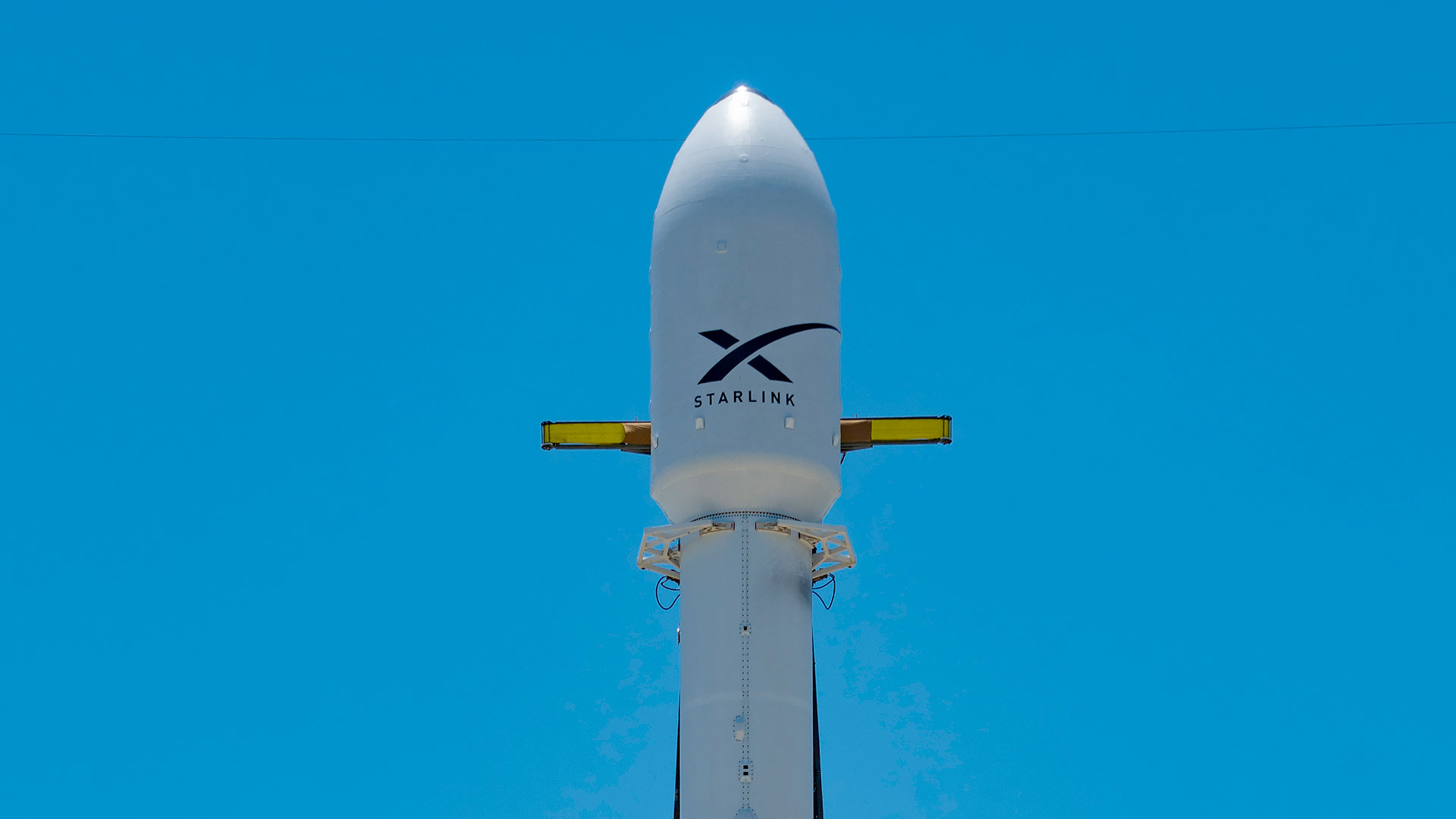 航天图片资料 · A white rocket topped with a payload fairing stands on the launch pad in a close-up set against a blue sky.