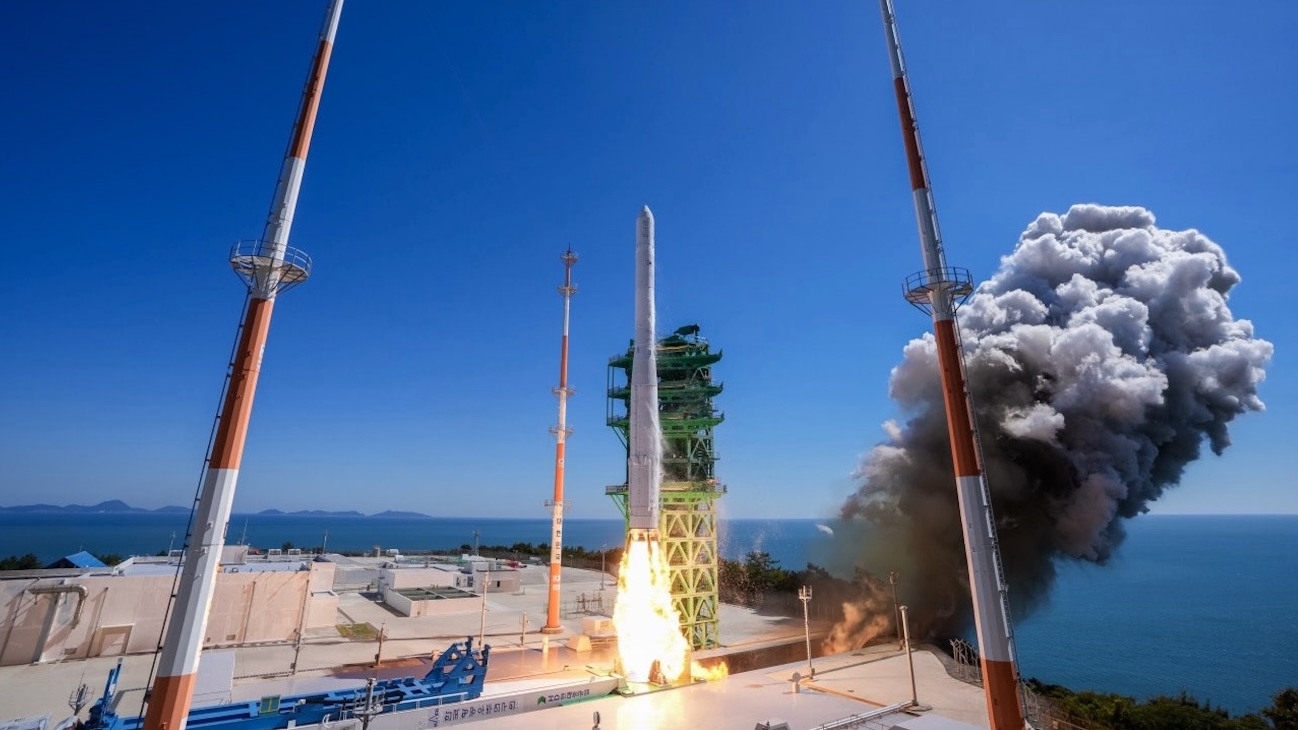 航天图片资料 · a white rocket launches into a blue sky from a seaside pad